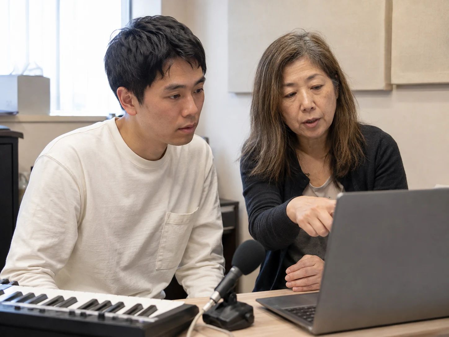 Adult singing student and teacher discussing a result beside a keyboard